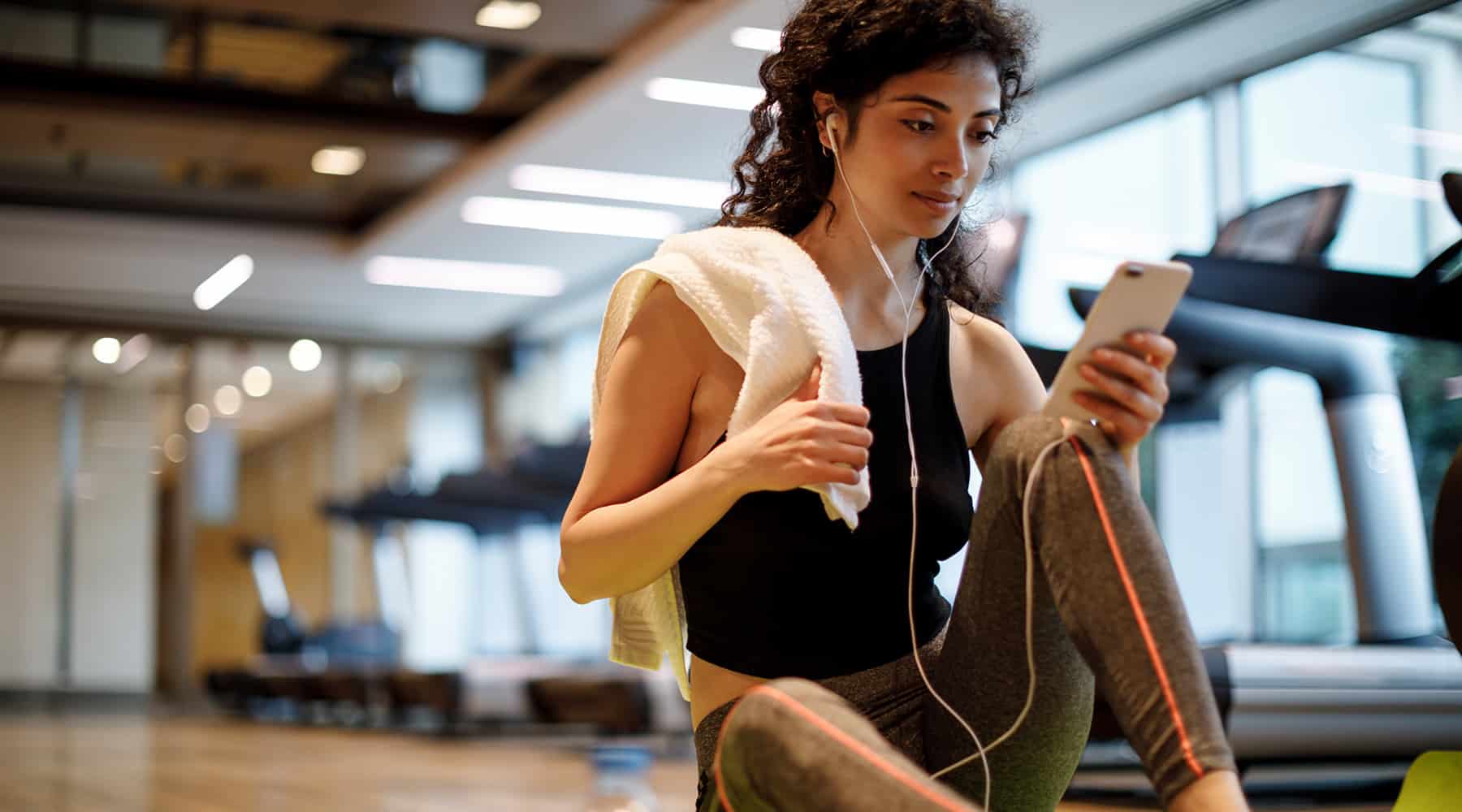 A woman takes a break and listens to music in modern fitness room in Concorde, CA
