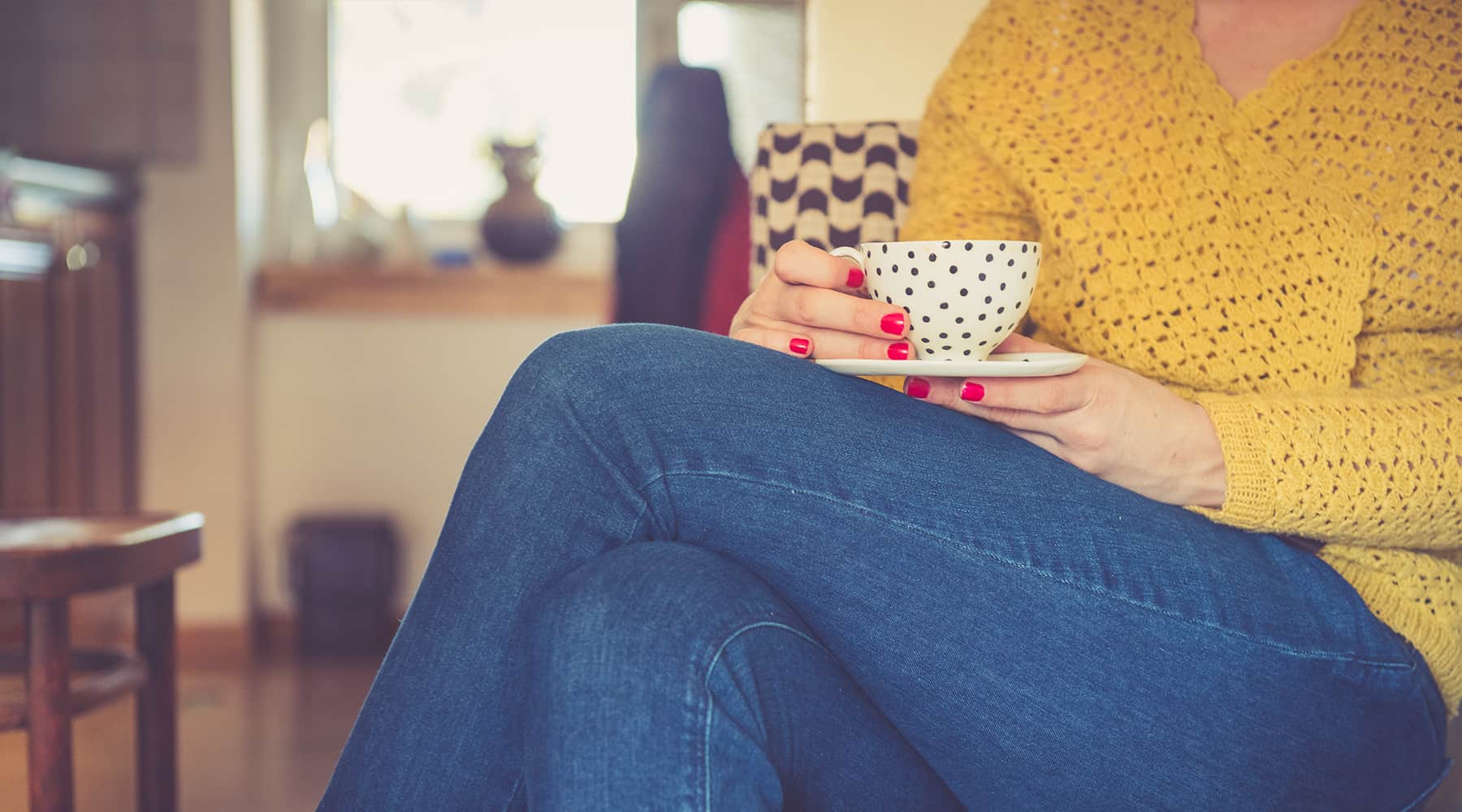 A woman sitting, holds a tea cup in her hands at her apartment in luxurious Renaissance Square.