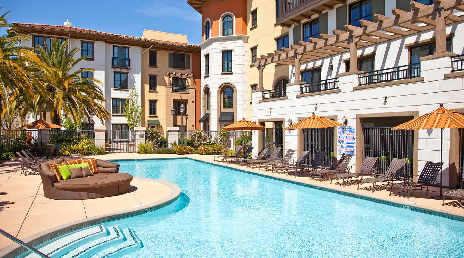 Upscale outdoor swimming pool area, with sunbeds and rattan lounge couches in Concorde, CA apartments